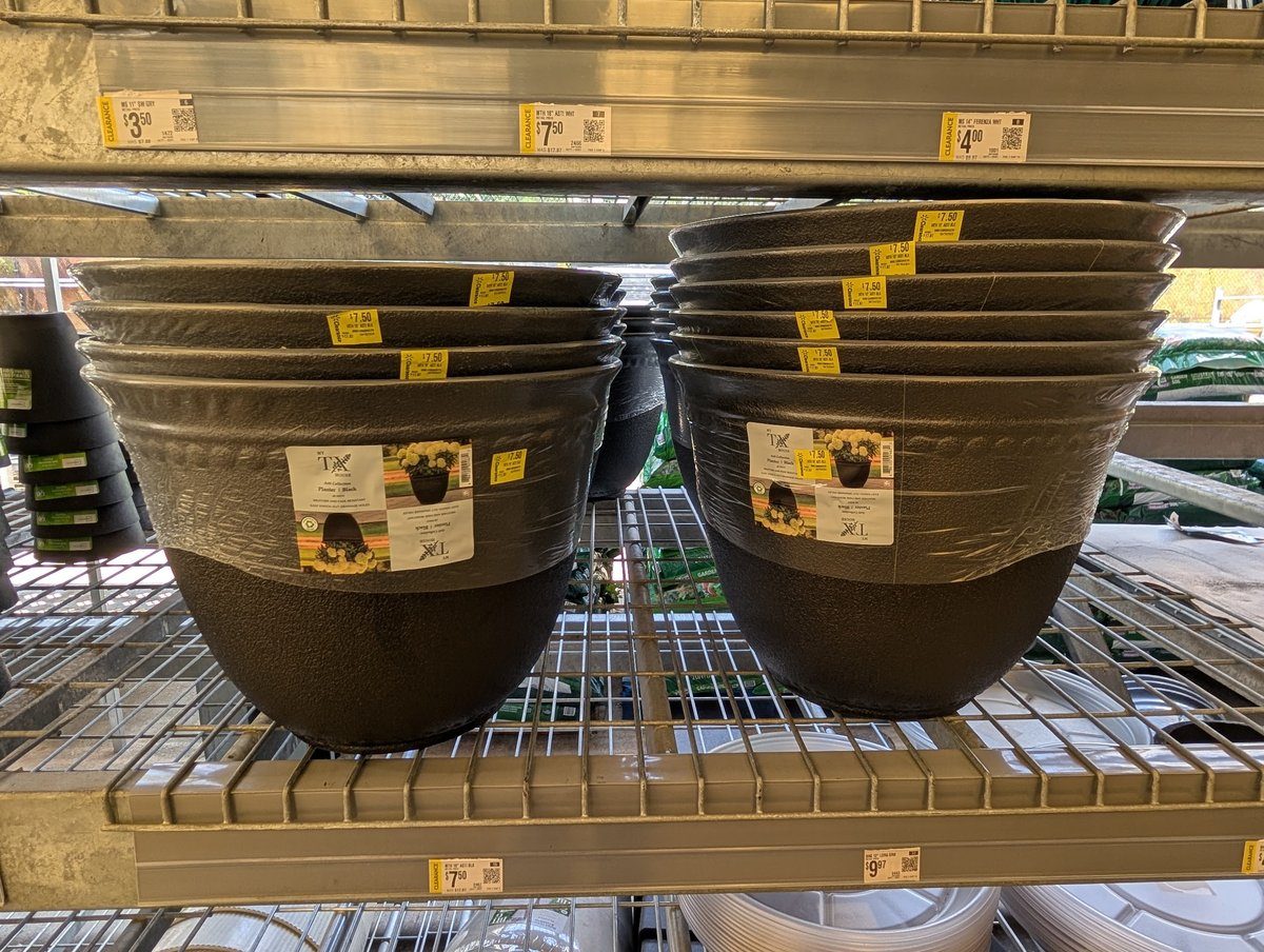 Stacks of 18-inch black resin planters on a big-box clearance shelf, marked down to $7.50 from $17.97