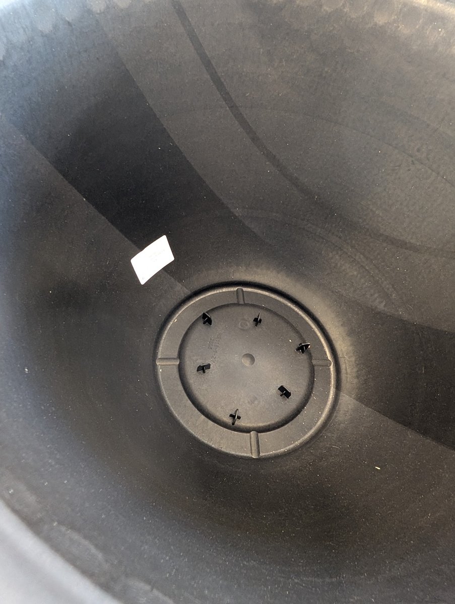 Inside bottom of a resin planter showing unopened drill markings for optional drainage, so the pot holds water