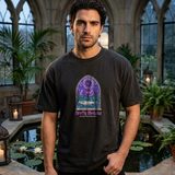 Man with dark wavy hair wearing the Cathedral Pond tee in Black, in a stone conservatory with gothic windows and a lily pond