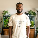 Man with a short beard wearing the Currently Cycling tee in Ivory, in a living room in front of a large planted aquarium