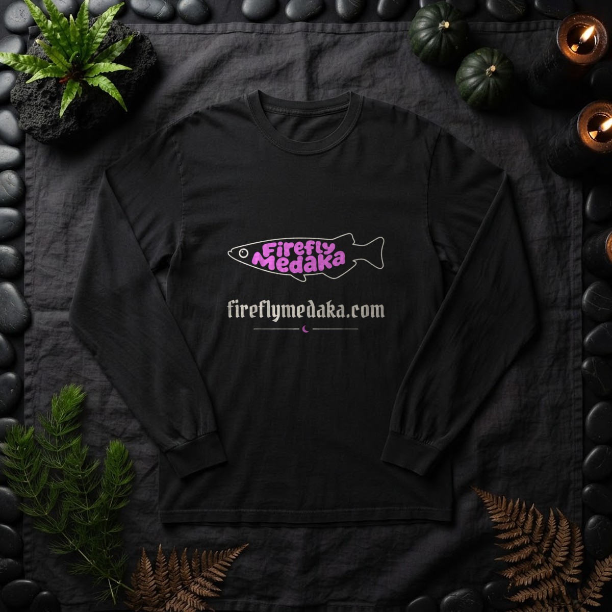 Firefly Medaka Nightshade logo long sleeve shirt in black on charcoal linen framed by black river stones, java fern on lava rock, hornwort, dark gourds, and pillar candles