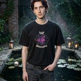 Man with dark auburn hair wearing the Nocturne logo tee in Black, by a moonlit garden pond with lily pads