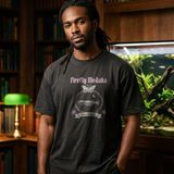 Man with locs wearing the Lux in Tenebris tee in Black, in a wood-paneled library with a large planted aquarium