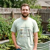 Man with a brown beard wearing the Medaka Strains Field Chart tee in Bay, in a backyard beside a stock tank pond with water lilies