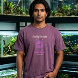 Man with jaw-length black hair wearing the Night Swim tee in Berry, in a fish room lined with planted aquariums