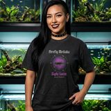 Woman with long black hair and a studded choker wearing the Night Swim tee in Black, in a fish room lined with planted aquariums